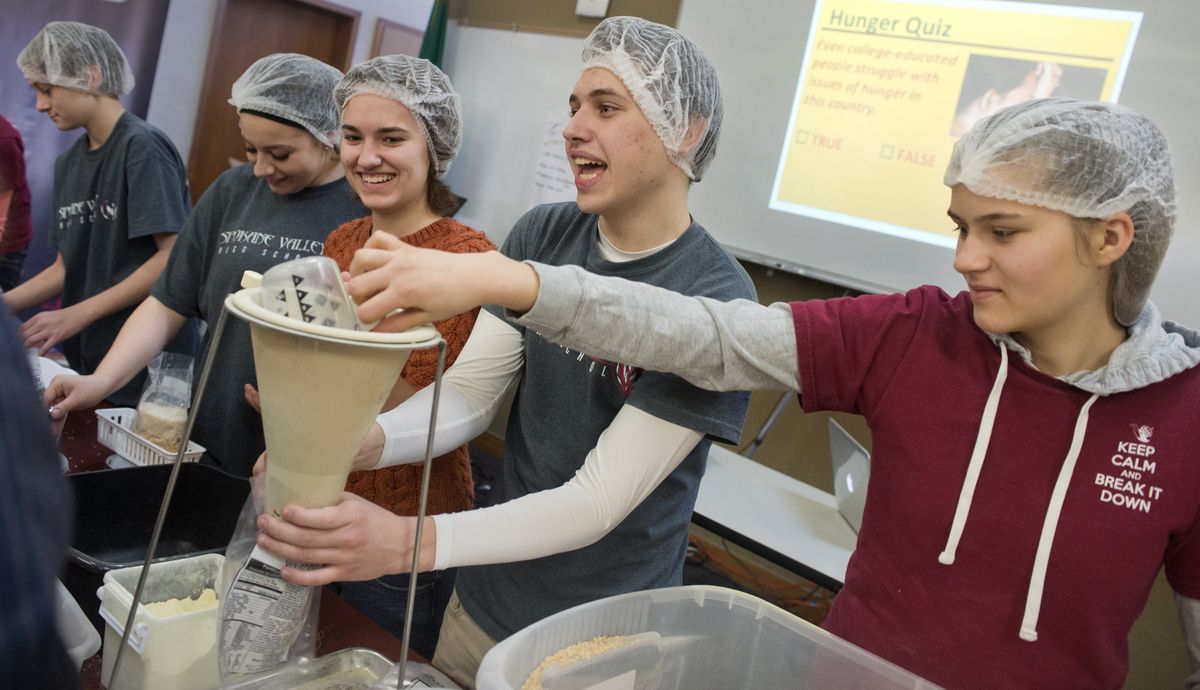 Spokane Valley High School students, from left, Benjamin Toole, Khylee Williams, Shannon Brandvold, Gleb Liashedko and Angelina Chebotareva, mix rice, soy protein and flavorings into plastic bags Thursday to donate to Second Harvest. The students’ Abolish Hunger project was part of their curriculum, touching several subjects. (Jesse Tinsley)