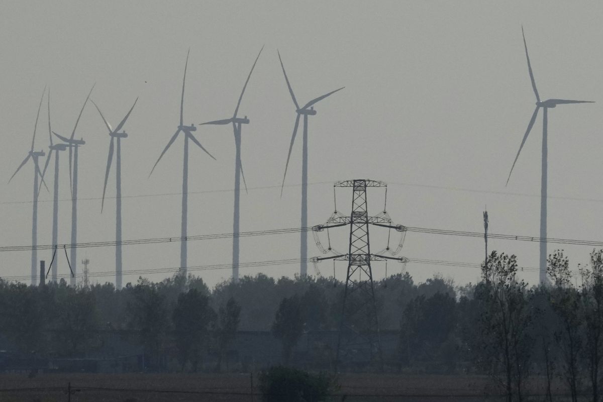 Wind turbines are seen near a power line near central China