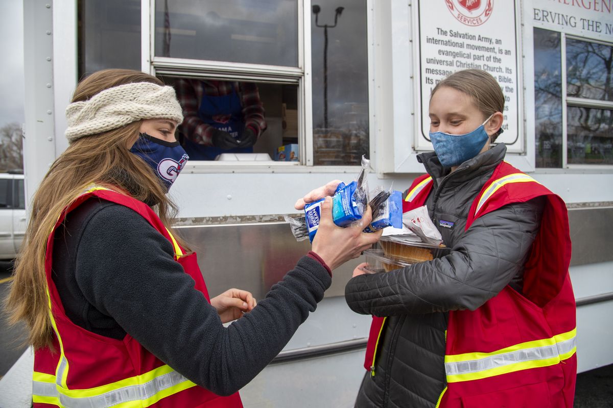 Volunteers Joy Oakes, left, and Delaney Yehle, both Gonzaga college students, load their arms with pumpkin pie, utensils and napkins while serving hot Thanksgiving meals to drive-through recipients at the Salvation Army headquarters in Spokane, Thursday, Nov. 25, 2020.  (Jesse Tinsley/The Spokesman-Review)