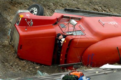 
Idaho State Police officer Gerry Stemm squeezes out of a truck cab on Tuesday while investigating a crash on Interstate 90 on the eastern edge of Coeur d'Alene on Tuesday morning. The truck dumped its load in the oncoming lane while descending into Coeur d'Alene. The spilled decking boards, caused a crash, injuring several people. 
 (Photos by Jesse Tinsley/ / The Spokesman-Review)