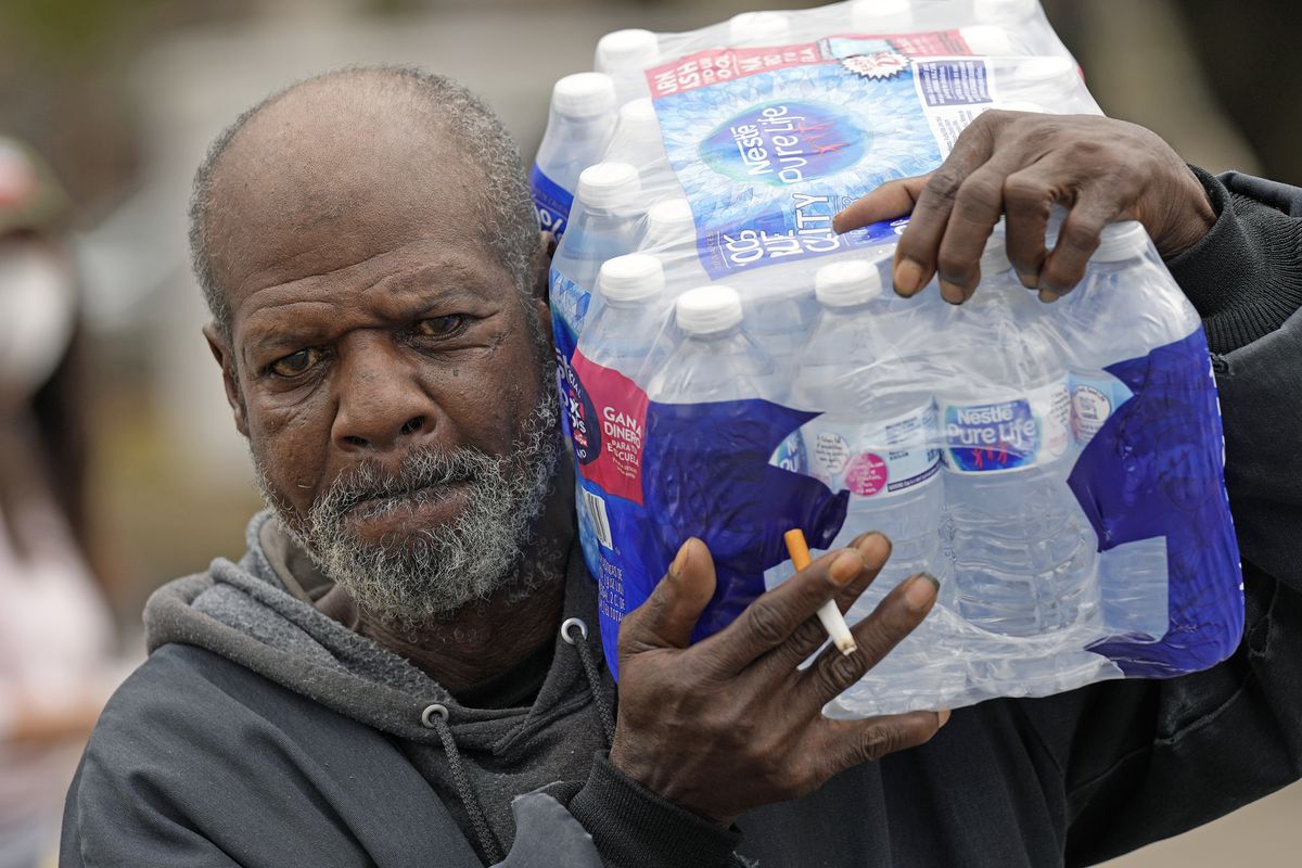 Kenneth Henderson carries a case of donated water back to his home, which was without running water after the recent winter storm, on Feb. 26 in Houston.  (David J. Phillip)