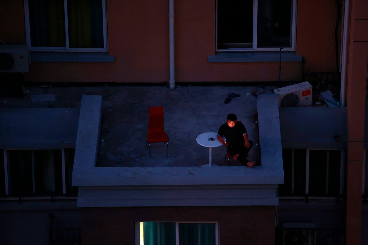 A man looks at his smartphone on a balcony in a residential community in Shanghai, China, Monday, April 11 2022. The U.S. has ordered all non-emergency consular staff to leave Shanghai, which is under a tight lockdown to contain a COVID-19 surge. Many residents in the city of 26 million have been confined to their homes for up to three weeks as China maintains its "zero-COVID" strategy of handling outbreaks with strict isolation and mass testing.  (STR)
