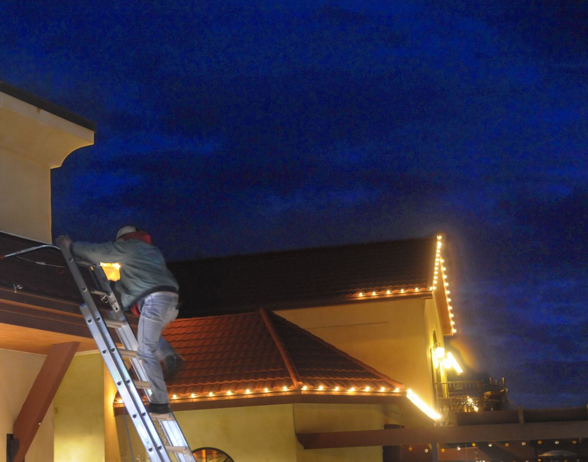 Tom Sanders climbs down his ladder while placing decorative white lights to outline the roof of Twiggs Bistro and Martini Bar on South Regal in Spokane.  (Christopher Anderson / The Spokesman-Review)
