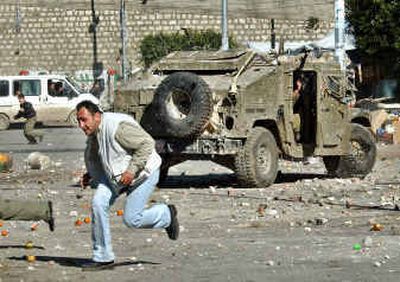 
Palestinians run for cover as Israeli soldiers shoot rubber bullets during clashes during an Israeli army patrol in the West Bank city of Nablus on Tuesday. 
 (Associated Press / The Spokesman-Review)