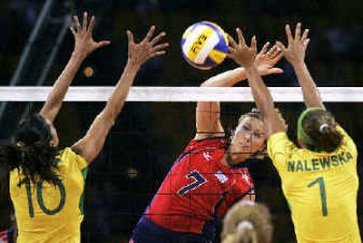 
USA's Heather Bown (7) spikes the ball between Brazil's Virna Dias (10) and Walewska Oliveira (1) during their volleyball quarterfinal round match .
 (Associated Press / The Spokesman-Review)