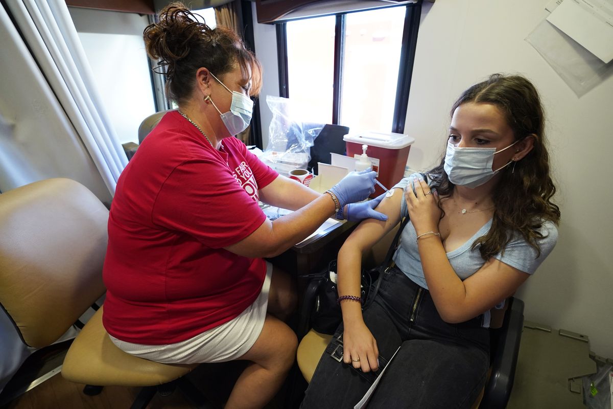 Hy Vee pharmacist Tiffany Aljets, left, gives a COVID-19 vaccination shot to eighteen-year-old exchange student Jonila Shehu, of Kosovo, Monday, Aug. 16, 2021, in Des Moines, Iowa. At the Iowa State Fair in Des Moines, where a million people are expected for the 11-day event, public health officials hope a vaccination station set up by pharmacists working for the Hy Vee food store chain will entice some of the vaccine-hesitant to get their shots. Visitors are packing in to state fairs in multiple Midwest states as COVID activity is increasing, raising concerns about the potential for rapidly accelerating spread of the delta variant of the COVID-19 virus. (Charlie Neibergall)