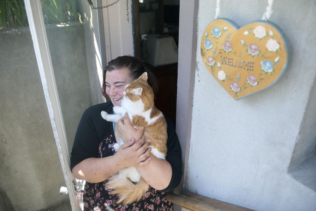 Raevn DeAugustino, after several years living on the street, stands with her cat Leo in the doorway of a modest basement apartment Wednesday, July 12, 2017. She ran away from home and lived on the Spokane streets, in fear for her safety every day. A recent push by the city of Spokane, with help from SNAP, is putting formerly homeless youth, like DeAugustino, into housing. (Jesse Tinsley / The Spokesman-Review)