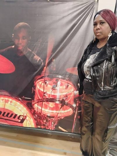 Drey Davis’ mother Erica stands next to a tapestry depicting an image of Drey playing drums.  (Courtesy)