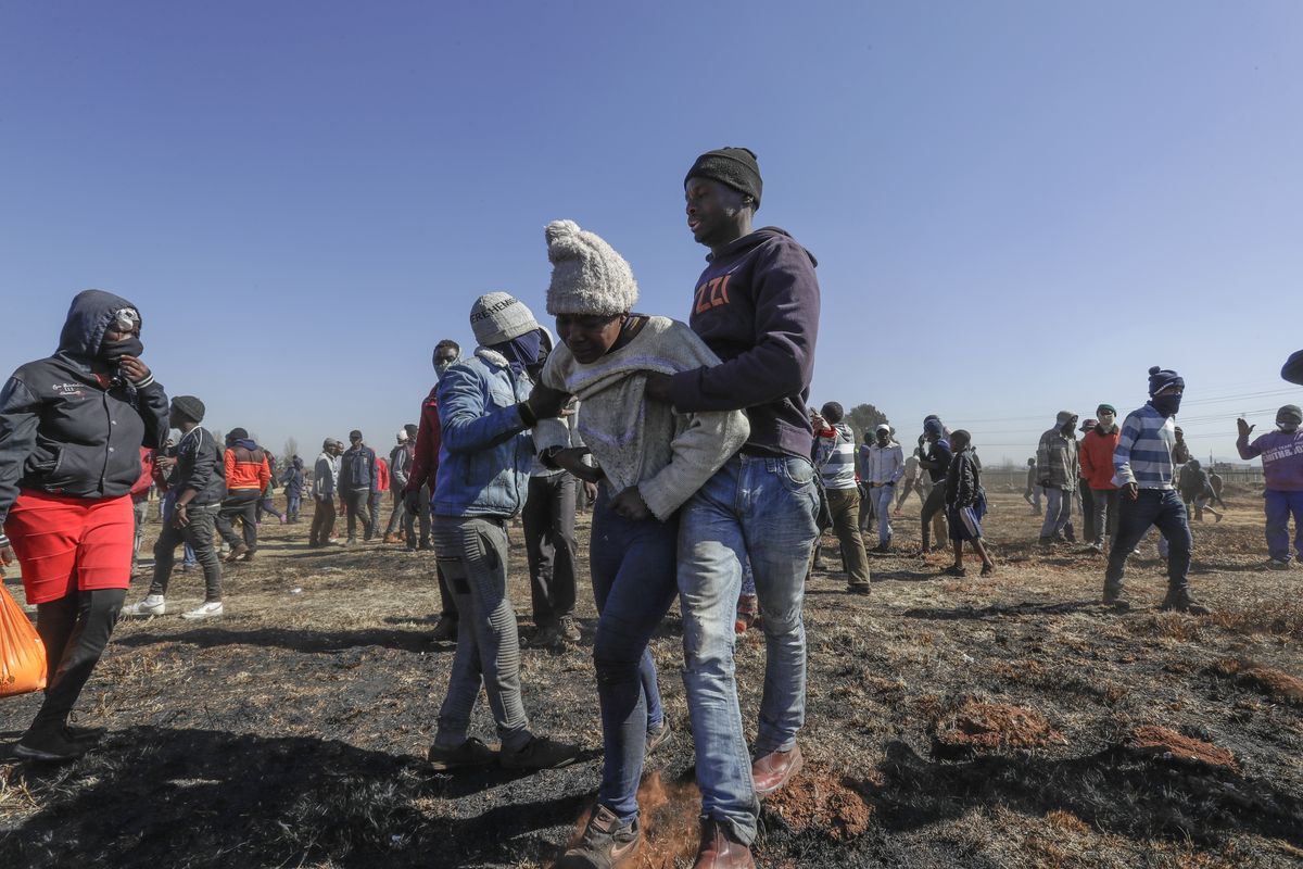 Residents help a family member of a 14-year-old boy who was shot during protests in Vosloorus, east of Johannesburg, South Africa, Wednesday July 14, 2021. South Africa