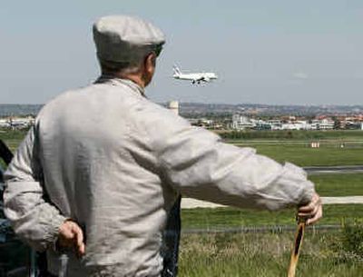 
An man who came to get a glimpse of the Airbus A380, the world's largest airliner, watches an Air France passenger plane land near Toulouse, France. 
 (Associated Press / The Spokesman-Review)