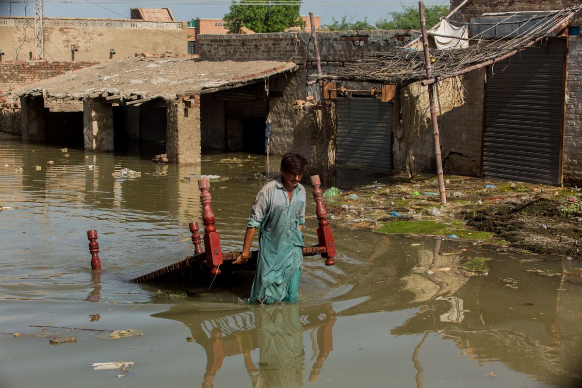 A man drags a table through flood waters in Pakistan.   (Asim Hafeez/Bloomberg)