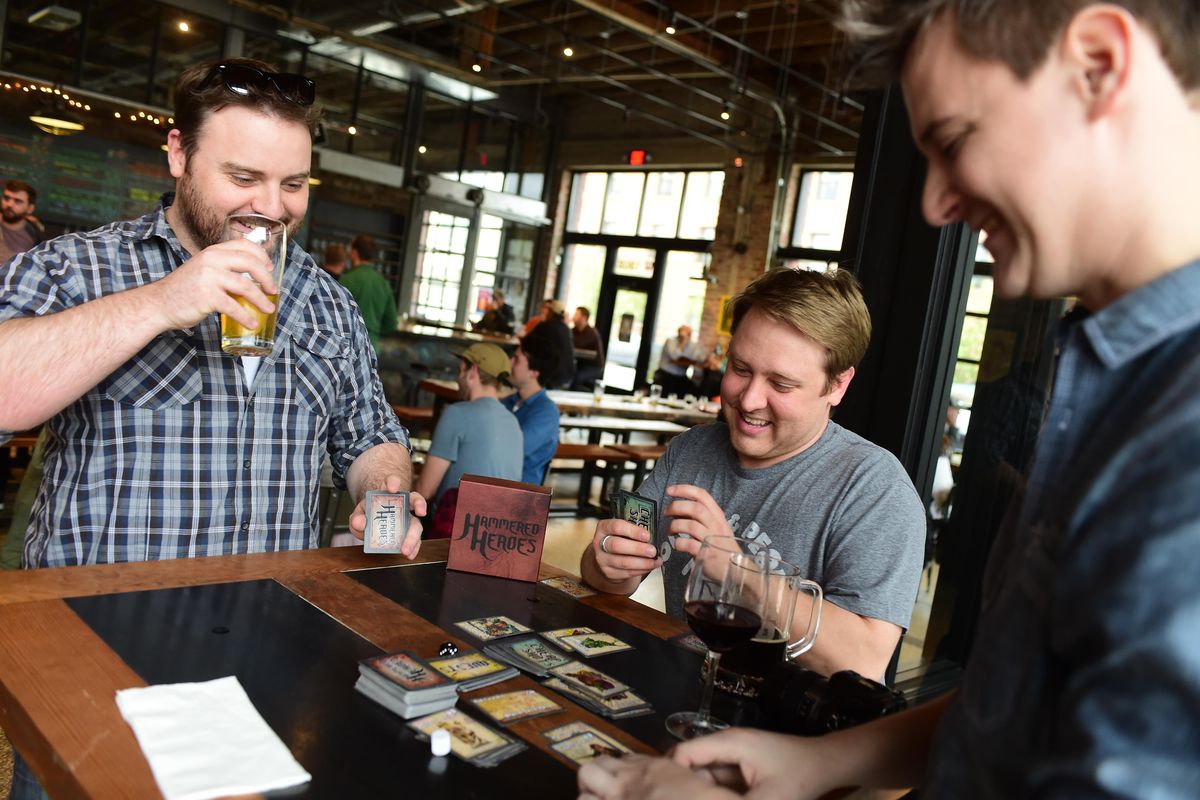 Clancy Bundy, Adam Boyd and Adam Harum, developers of the drinking and card game Hammered Heroes, play at a table in the Iron Goat Brewing tap room in May. The game is up for crowdfunding at Kickstarter. (Jesse Tinsley / The Spokesman-Review)