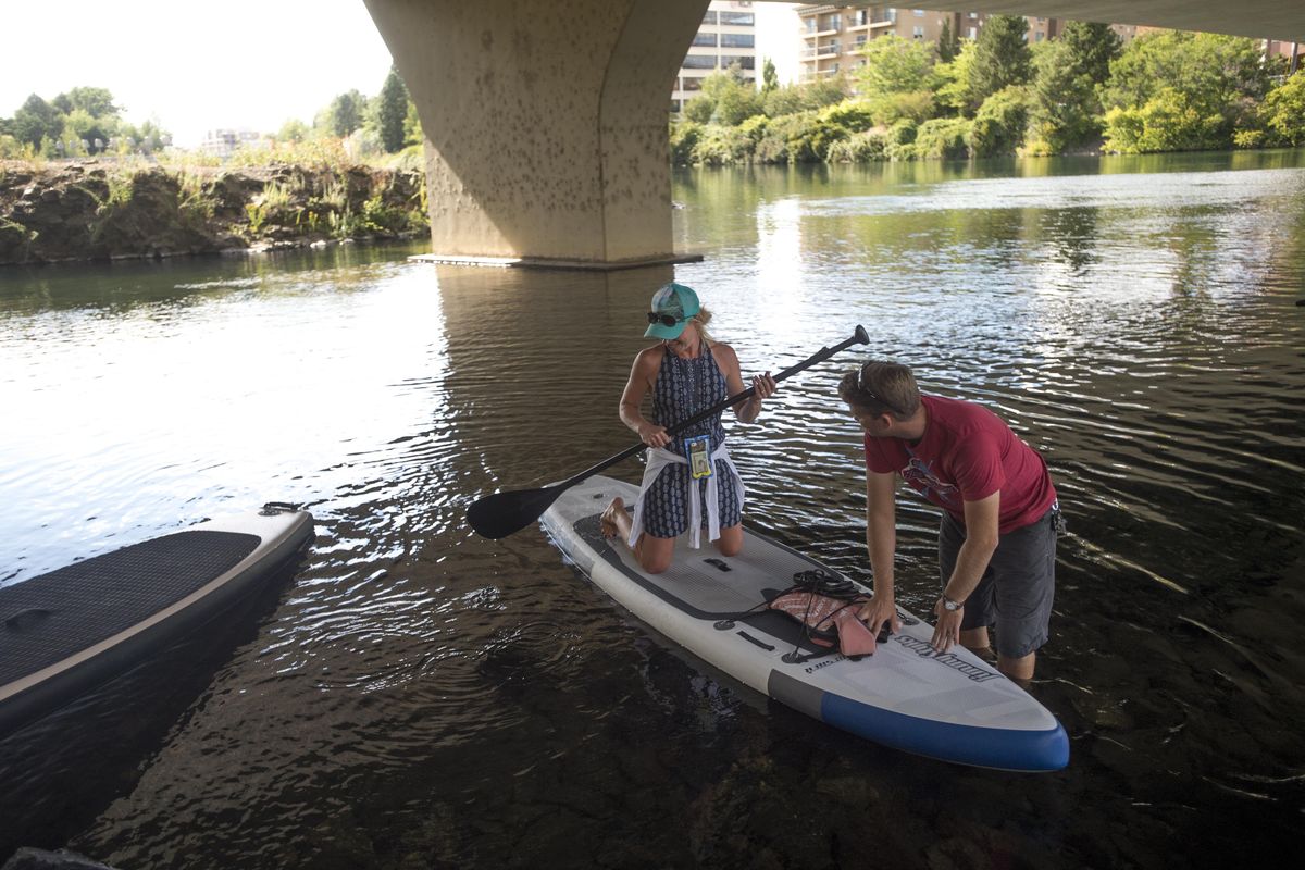Keith Quien helps Rachael Krum with a paddle board before she takes to the Spokane River on a tour with Fun Unlimited on Wednesday, July 13, 2016, in Spokane, Wash. (Tyler Tjomsland / The Spokesman-Review)