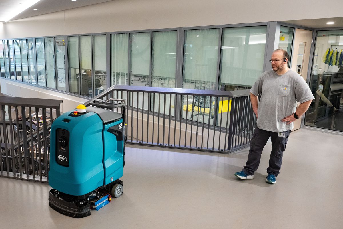 Glover Middle School custodial assistant Jason Huffman turns a janitorial robot floor cleaner loose on the hallways of the school, Tuesday, Feb. 4, 2026. Spokane Public Schools recently purchased a fleet of robots to clean the floors at each high school and middle school. It