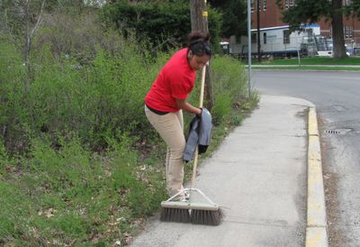 Erika Ambrocio, an Eastern Washington University freshman, sweeps up sand  along C Street.  (Lisa Leinberger / The Spokesman-Review)