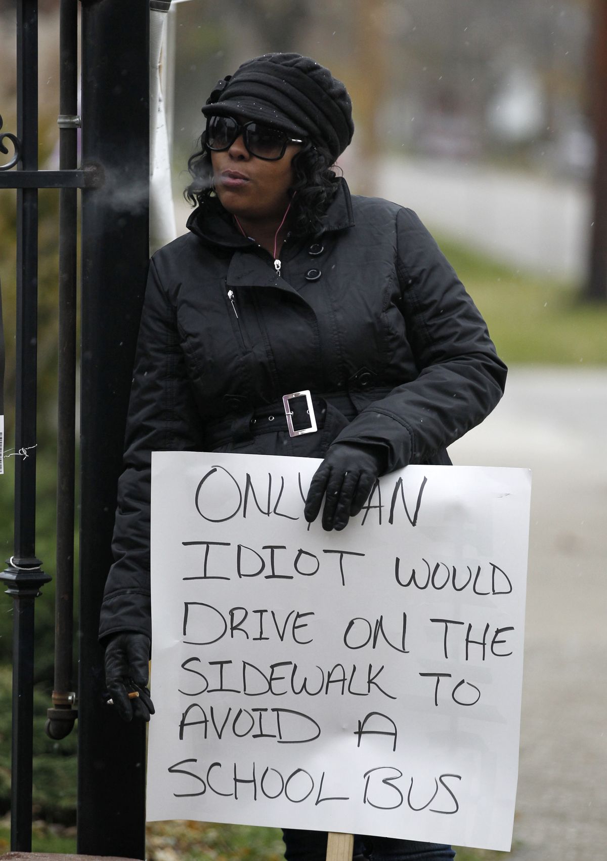 Shena Hardin smokes a cigarette as she holds up a sign to serve a highly public sentence Tuesday, Nov. 13, 2012, in Cleveland, for driving on a sidewalk to avoid a Cleveland school bus that was unloading children. A Cleveland Municipal Court judge ordered 32-year-old Hardin to serve the highly public sentence for one hour Tuesday and Wednesday. (Tony Dejak / Associated Press)