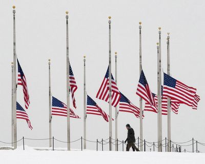 Visitors to the Washington Monument walk past flags flying at half-staff Monday in honor of Supreme Court Justice Antonin Scalia. (J. David Ake / Associated Press)