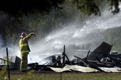 
A Spokane Valley firefighter takes care of hot spots after a barn fire Tuesday. 
 (Liz Kishimoto / The Spokesman-Review)