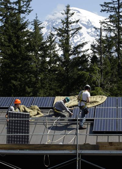Workers at Mount Rainier National Park install solar panels on the roof of the park’s Emergency Operations Center in 2009. Solar counts toward Initiative 937’s clean energy requirement. (Associated Press)