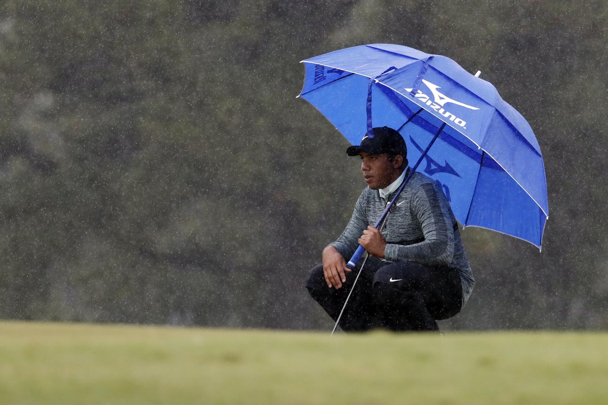 Jhonattan Vegas, of Venezuela, takes a knee in the rain as he waits for fellow golfers to take their putts on the 10th green during the first day of the Sanderson Farms Championship golf tournament in Jackson, Miss.,Thursday, Oct. 25, 2018. (Rogelio V. Solis / Associated Press)