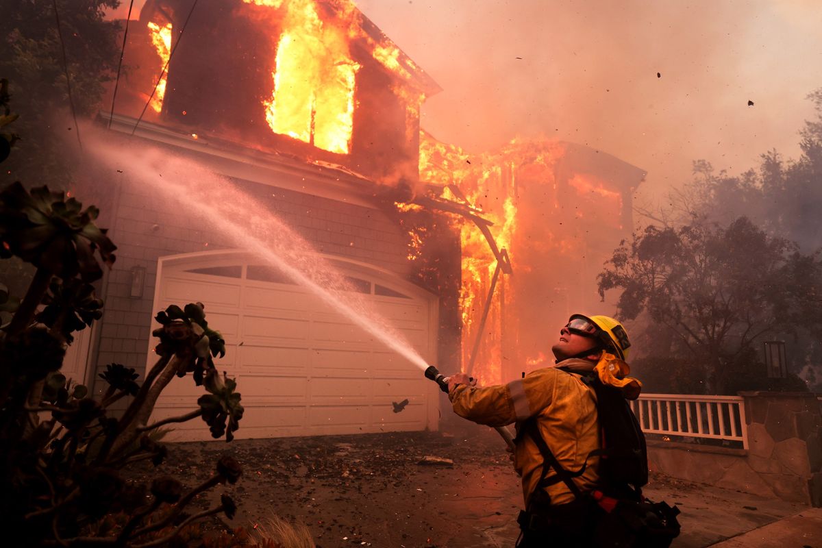 Firefighters battle a house fire off Bollinger Drive in Pacific Palisades, California, after a brush fire spread quickly Tuesday with heavy winds.  (Wally Skalij/Los Angeles Times)