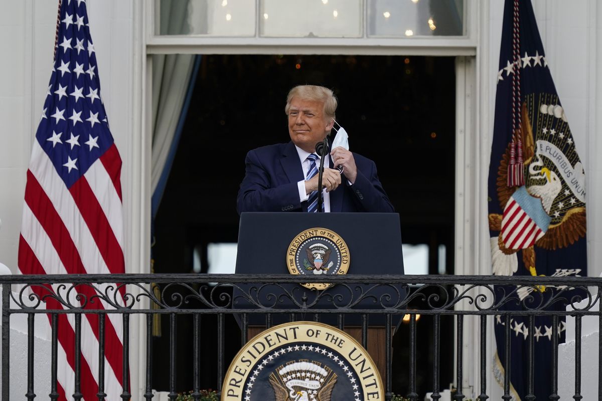 President Donald Trump removes his face mask to speak from the Blue Room Balcony of the White House to a crowd of supporters Saturday, Oct. 10, 2020.   (Alex Brandon)