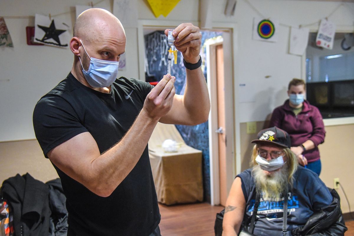 WSU nursing student Dane Lawson loads up a second Moderna COVID-19 vaccine for Mike Partridge, 65, right, during a Spokane Regional Health District vaccine clinic March 2 at the House of Charity in downtown Spokane.  (DAN PELLE/THE SPOKESMAN-REVIEW)