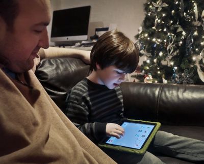Adam Cohen watches as his son Marc, 5, uses a tablet at their home in New York. Tablets are expected to rank among the top holiday gifts for children this year, but some experts and advocates question the educational or developmental benefits for youngsters. (Associated Press)