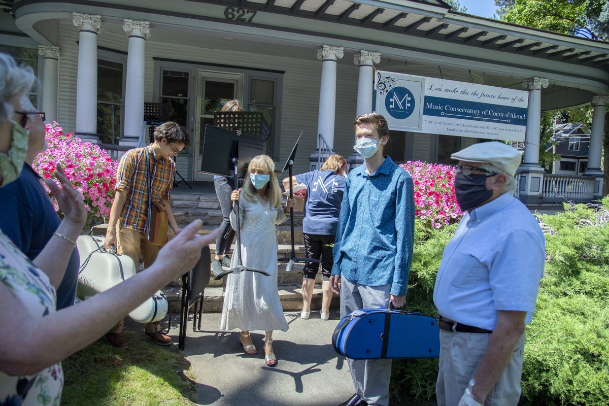 Outside the 1908 house at 627 Government Way in Coeur d’Alene, which is a home built for Boyd Hamilton, a banker and second mayor of Coeur d’Alene, supporters of a new music school gather at an open house, Monday, July 27, 2020. Zoe Ann Thruman carries signs and other equipment for the opene house Monday. The home, which sits near the courthouse and was a lawyer’s office for many years, was set to be torn down but a group of local people proposed it be used as a music conservatory and are raising the money to buy it, if it can be done. Shown Monday, July 27, 2020. The county, which planned to use the historic home site for a new office building, has given the music proponents a limited time to buy the property.  (Jesse Tinsley/The Spokesman-Review)