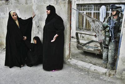 
A U.S. Army soldier stands guard while women cry after soldiers kicked through their front gate in the Shula section of Baghdad, Iraq, on Thursday. 
 (Associated Press / The Spokesman-Review)