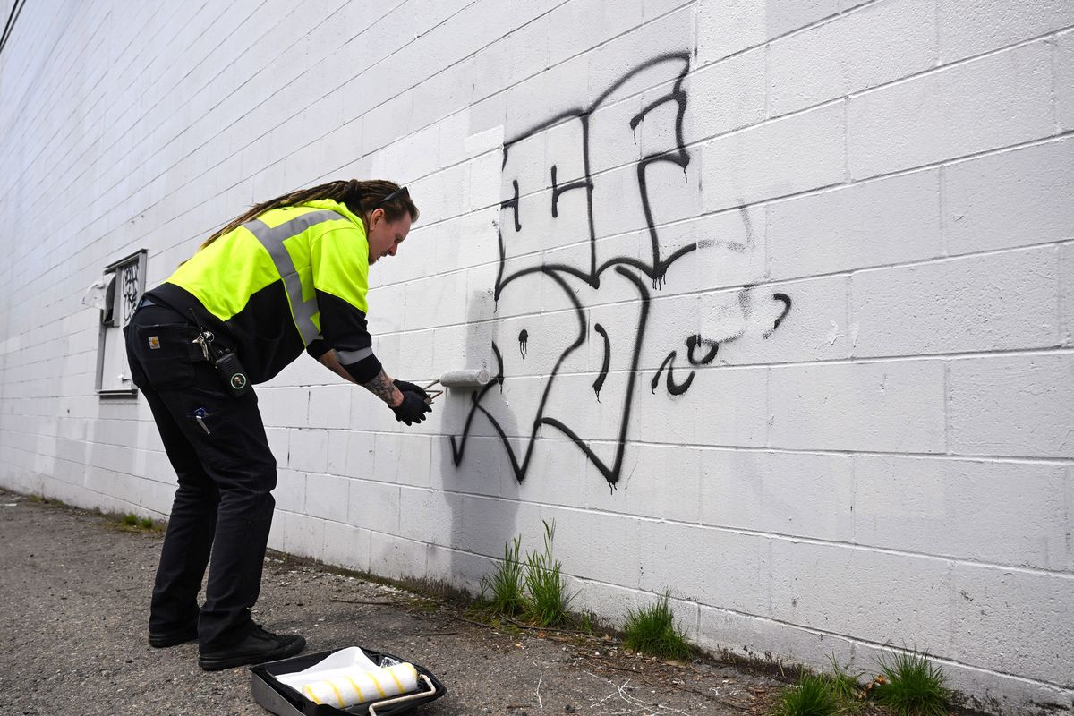 Chris Rosdahl, of the Downtown Spokane Partnership’s Clean Team, paints over graffiti on a wall behind the Subaru of Spokane auto dealership Tuesday. The team cleans year-round but is giving the city extra attention with the women’s NCAA Tournament in town beginning Friday.  (Jesse Tinsley/THE SPOKESMAN-REVI)