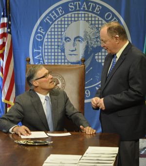 OLYMPIA -- Gov. Jay Inslee and Sen. Mike Padden, R-Spokane Valley, talk before Inslee signs Padden's bill to allow medical examiners to discuss the results of autopsies of people who die in custody or in actions with police. (Jim Camden)