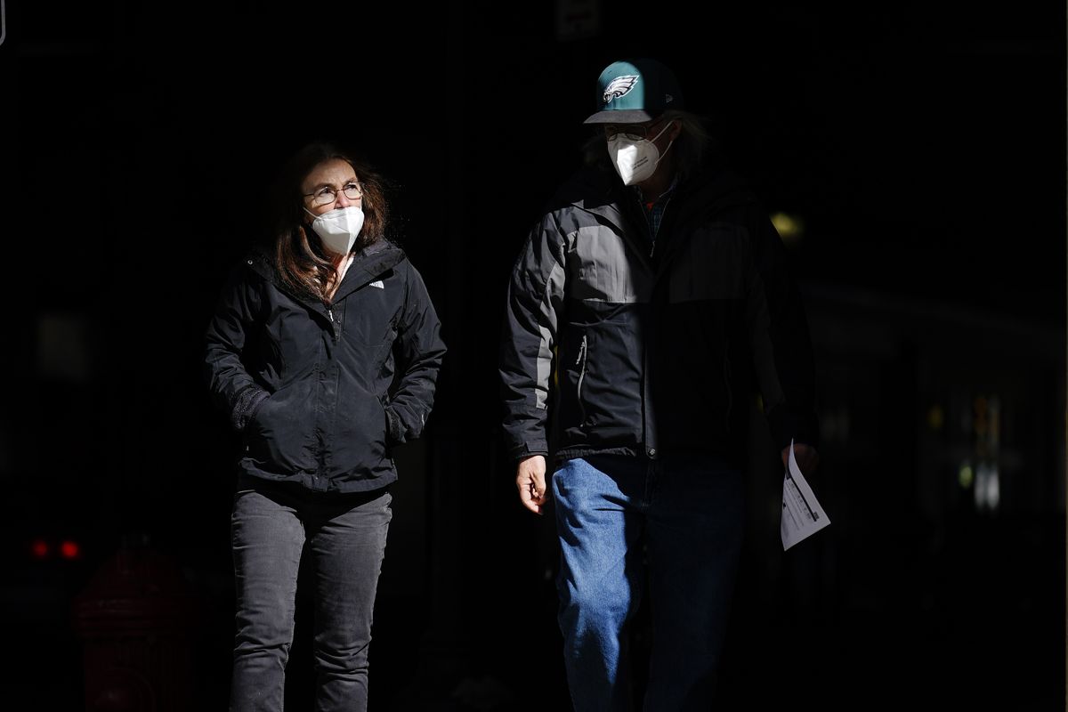 FILE - In this Wednesday, March 3, 2021 file photo, people wearing face masks as a precaution against the coronavirus walk through a shaft of light on a street in Philadelphia. On Tuesday, April 27, 2021, U.S. health officials say fully vaccinated Americans don