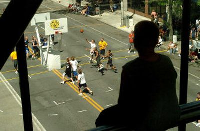 
Zach Goin, 12, of Pasco, watches his cousin Caleb Morgan, 14, ofDeer Park, drive to the basket from the relative cool of the STA Plaza overpass on Sunday. Thousands of Hoopfest fans and players looked for an escape from the afternoon heat as temperatures reached into the  90s.
 (Joe Barrentine / The Spokesman-Review)