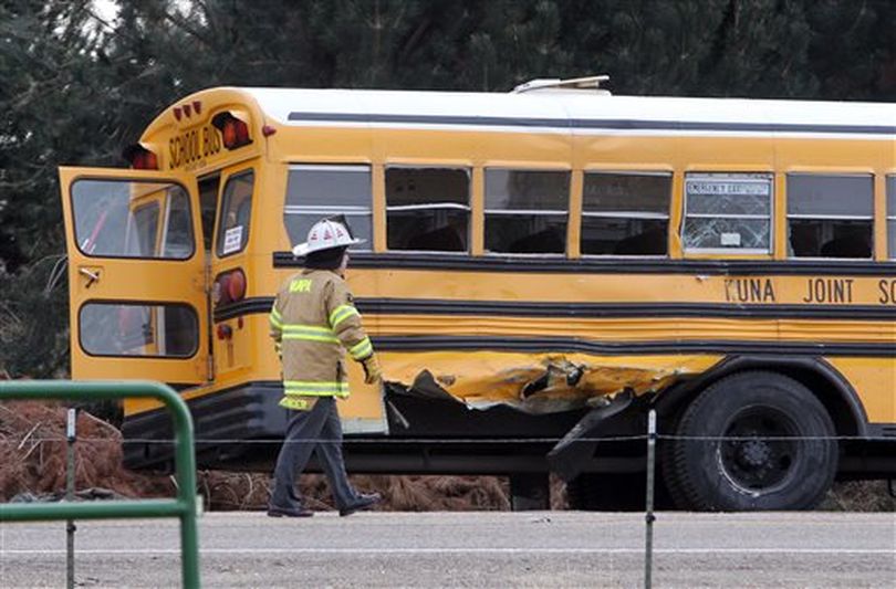 A firefighter walks past the damaged Kuna School District bus at the scene of a fatal crash on Thursday, Dec. 5, 2013 in Kuna, Idaho. Authorities say one child has died and at least four people were injured. (AP/Idaho Statesman / Darin Oswald)
