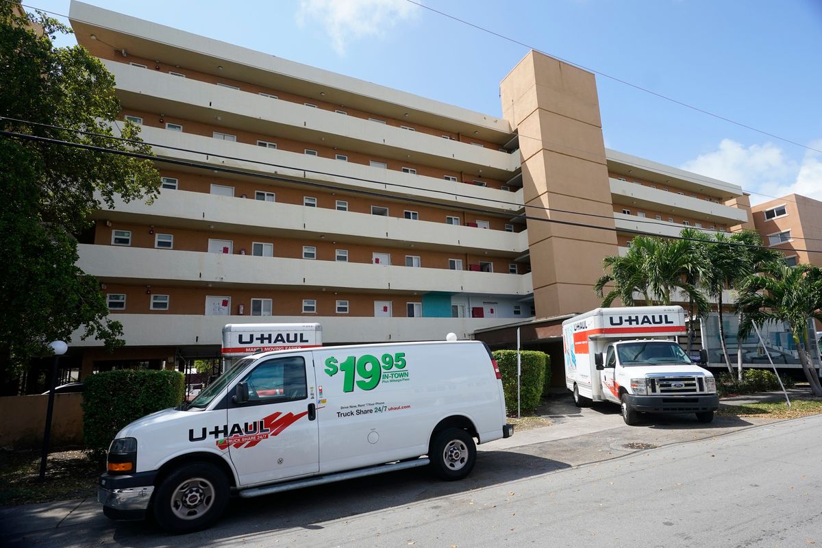 Moving vans and trucks are shown parked outside the Bayview 60 Homes apartment building, Tuesday, April 5, 2022, in North Miami Beach, Fla. City officials in North Miami Beach ordered residents of the five-story apartment building to evacuate after deeming the building "structurally unsound" during its 50-year recertification process.  (Wilfredo Lee)