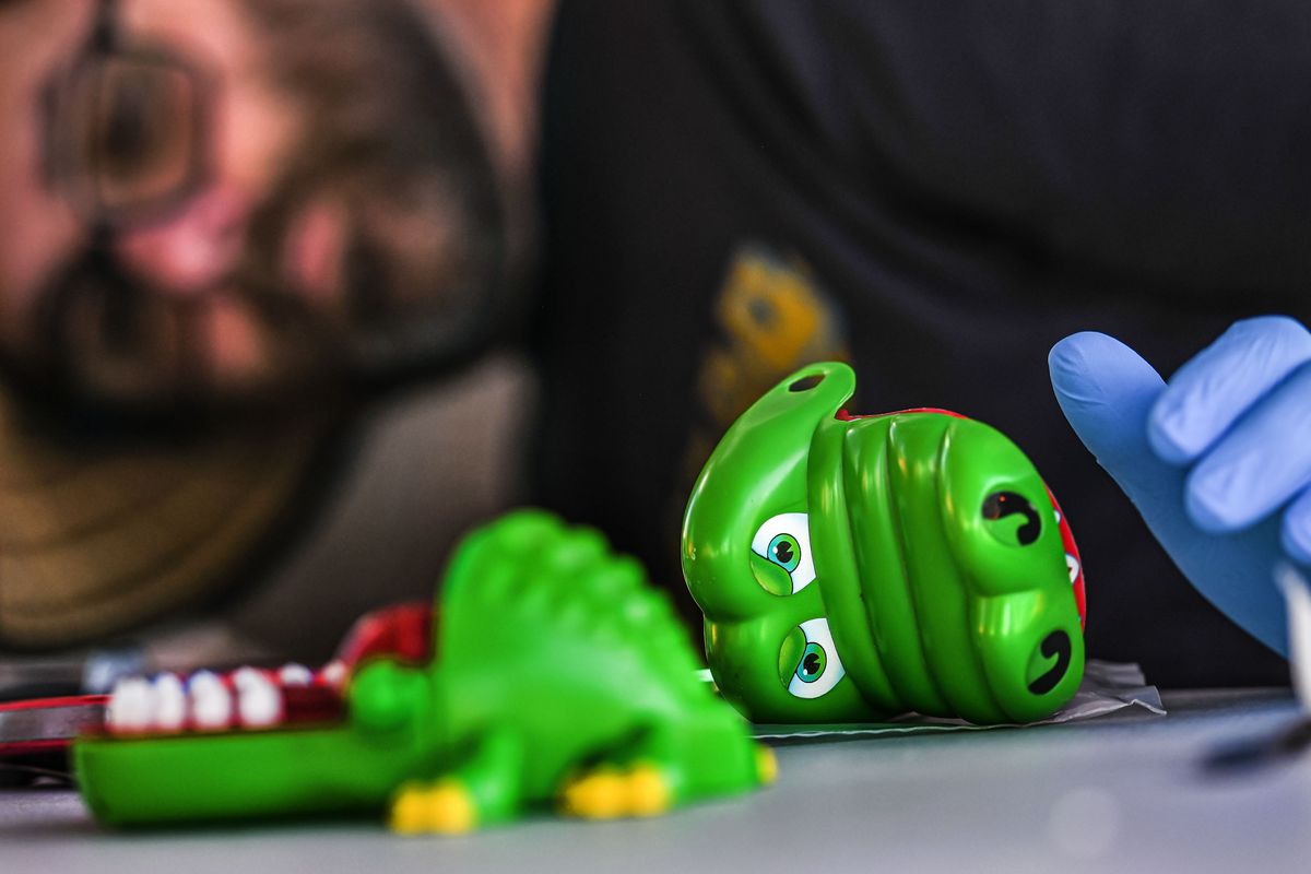 Chris Oxford works to fix Kent Larson’s grandson’s toy alligator in May at Repair Café at the Perry Street Market.  (Kathy Plonka/The Spokesman-Review)