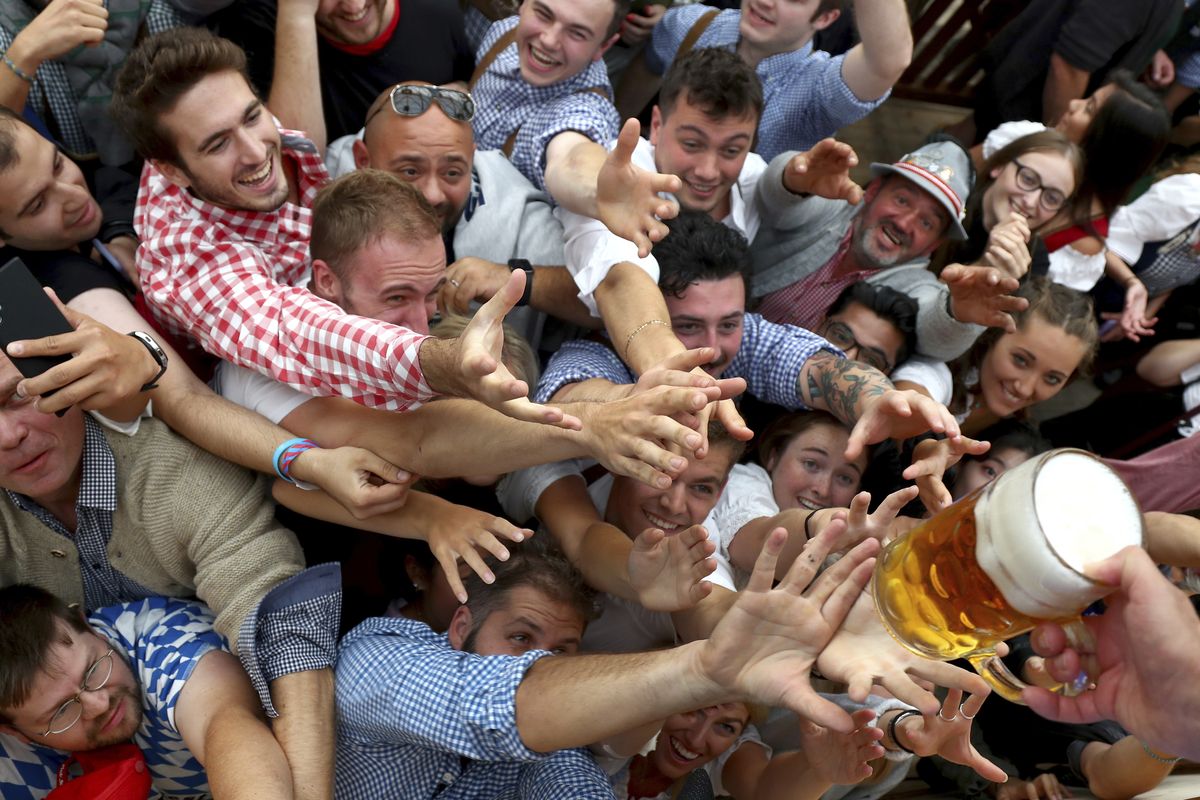 People reach out for a glass of beer Sept. 21, 2019, during the opening of the 186th “Oktoberfest” beer festival in Munich, Germany. Bavarian officials announced Monday they have canceled Oktoberfest festivities for the second year in a row due to concerns over the spread of the coronavirus global pandemic.  (Matthias Schrader)