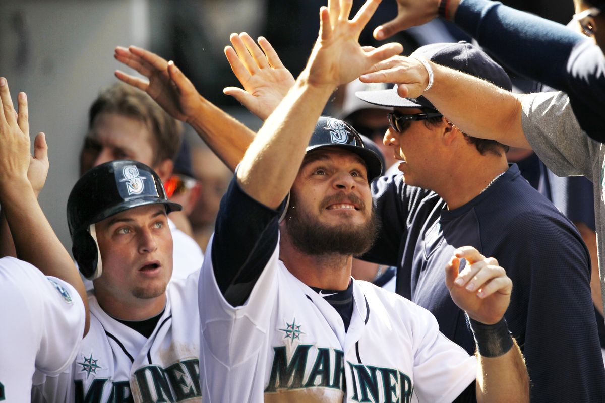 Seattle M’s John Jaso, front, and Kyle Seager, left, are congratulated in the dugout after they scored to give Seattle an eighth-inning lead. (Associated Press)