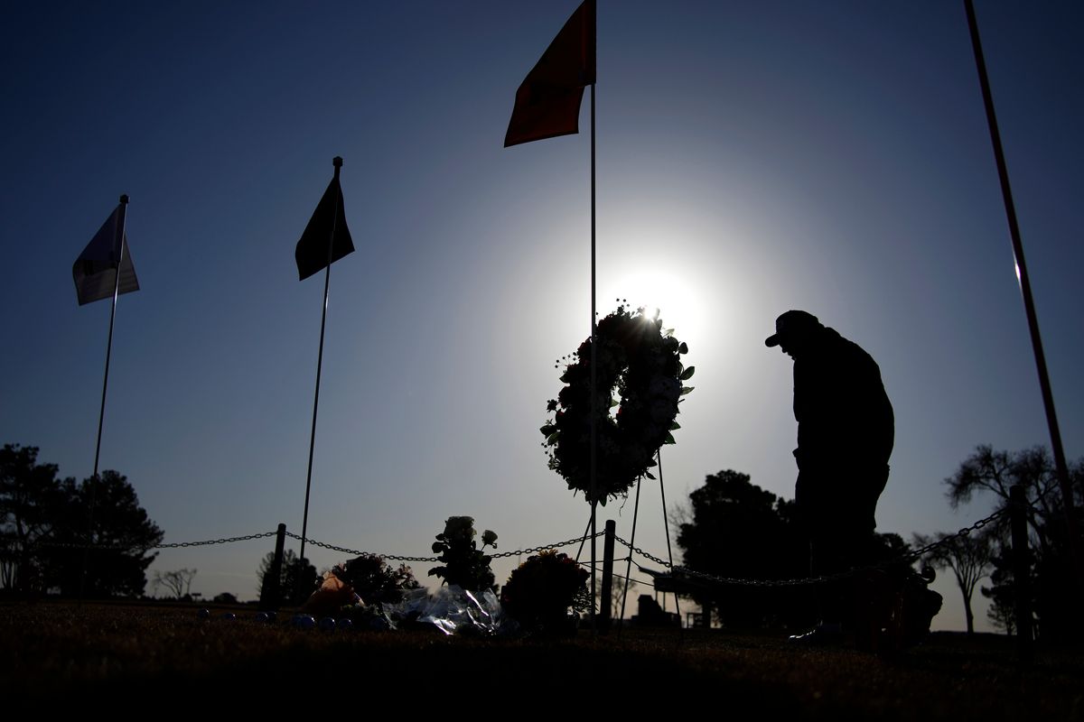 A golfer visits a makeshift memorial at the Rockwind Community Links Thursday, March 17, 2022, in Hobbs, New Mexico. The memorial was for student golfers and the coach of University of the Southwest killed in a crash in Texas.  (John Locher)