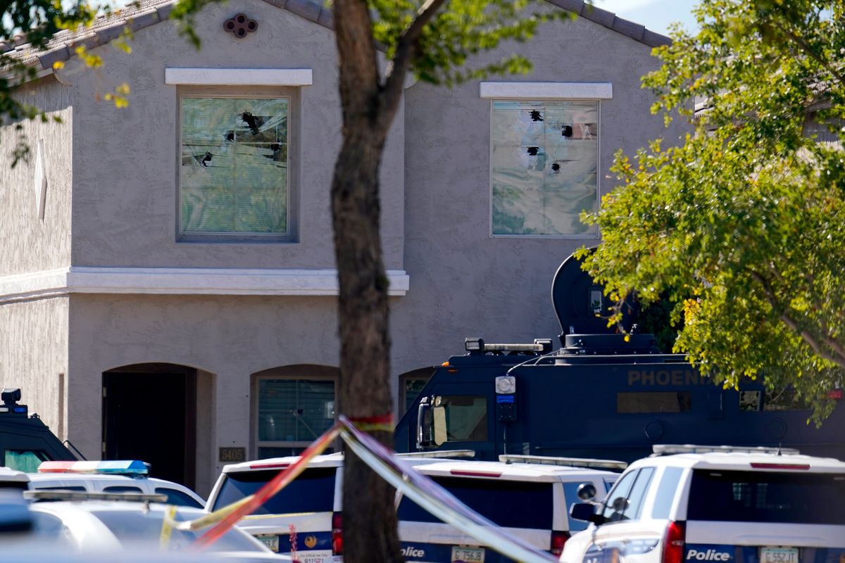 Multiple holes in windows can be seen at a house where five Phoenix Police Department officers were shot and four others were injured after responding to a shooting inside the home Friday, Feb. 11, 2022, in Phoenix. The shooting suspect was found dead in the home following a barricade situation, and a woman at the home was critically injured. (Ross D. Franklin)
