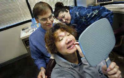 
Tao Yong holds a mirror and checks his new smile as Dr. Chris Chaffin watches Thursday. 
 (Christopher Anderson/ / The Spokesman-Review)