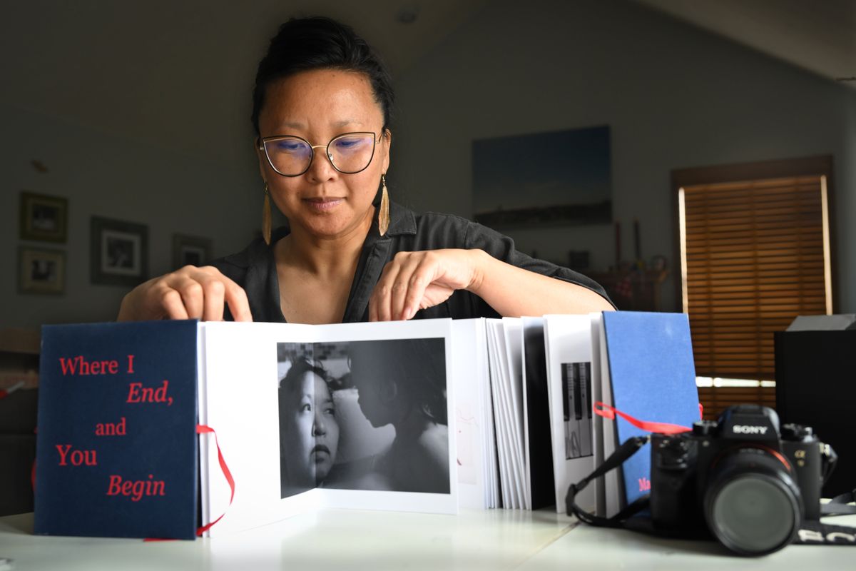Photographer Margaret Albaugh displays her accordion-fold book of photographs, prose and poetry called “Where I End And You Begin” on April 16 at her home in Spokane. The book delves into her life growing up as the daughter of Chinese immigrants and her own journey as a mother. (Jesse Tinsley/THE SPOKESMAN-REVIEW)