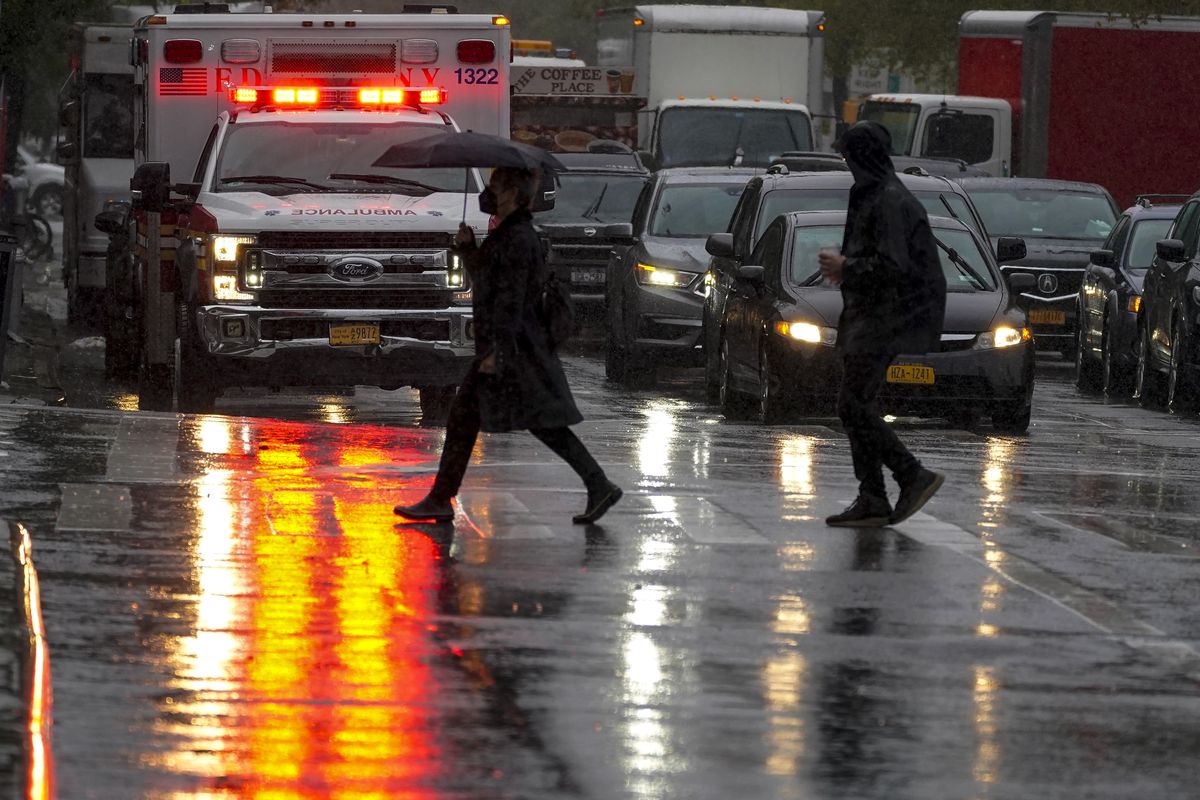 Pedestrians make their way across Delancey Street as rain falls, Tuesday, Oct. 26, 2021, in New York. A flash flood watch is in effect as a nor'easter moves through the New York metro area.  (Mary Altaffer)