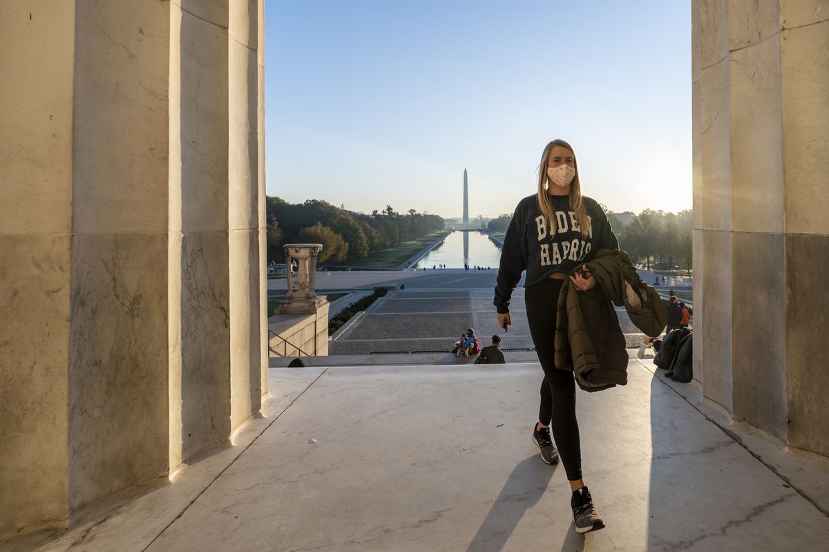 FILE - In this Nov. 8, 2020, file photo, a woman wears a Biden-Harris campaign shirt as she and others gather at the Lincoln Memorial at sunrise, Sunday, Nov. 8, 2020, the morning after incumbent President Donald Trump was defeated by his Democratic challenger President-elect Joe Biden. (J. Scott Applewhite)