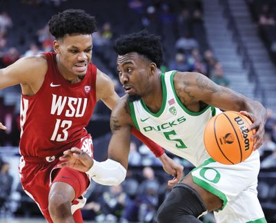 Washington State forward Carlos Rosario, left, defends against Oregon guard Jermaine Couisnard during a Pac-12 tournament quarterfinal round game on March 9 at T-Mobile Arena in Las Vegas. Rosario entered the NCAA transfer portal on Friday.  (Getty Images)