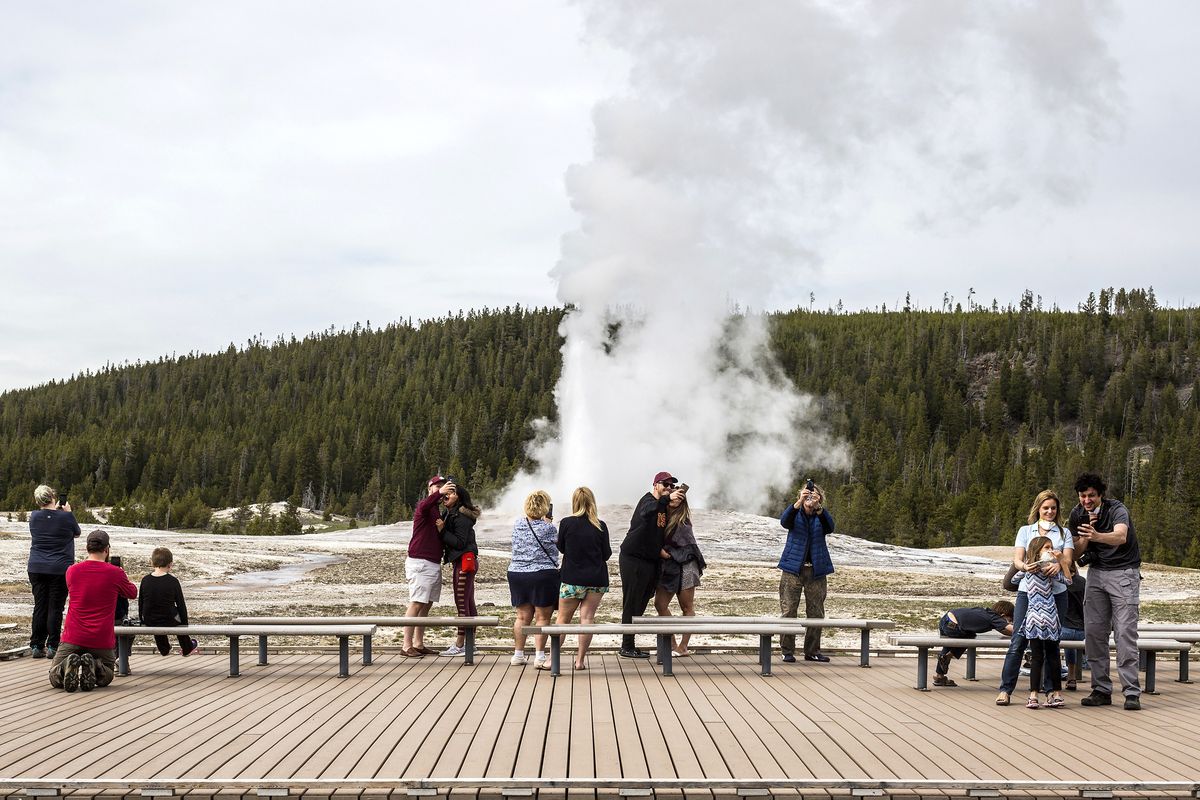 FILE - In this May 18, 2020, file photo, visitors watch as Old Faithful erupts at Yellowstone National Park, Wyo. Americans may soon get a better glimpse into a future of green-friendly transportation by visiting a U.S. national park. It’s a joint pledge being signed Wednesday by Interior Secretary Deb Haaland and Transportation Secretary Pete Buttigieg to test some of the newest and most innovative travel technologies on public lands. The plan is being made possible by the $1 trillion infrastructure law and other federal spending. Under new pilot programs, visitors to national parks could see self-driving shuttle buses, along with more electric scooter or bike stations and electric charging stations for travelers in zero-emission cars. Yellowstone National Park would see some of the most immediate updates, with other sites to follow. (Ryan Dorgan)