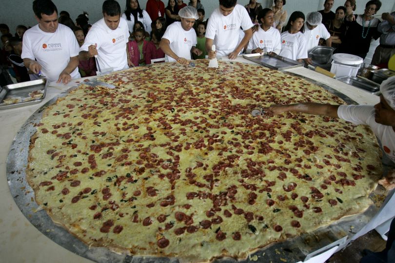 Pizza chefs cut pieces from a large pizza in Sao Paulo, Saturday July 10, 2010.  Sao Paulo's Tourism Office celebrated World Pizza Day on Saturday. (Nelson Antoine / Associated Press)