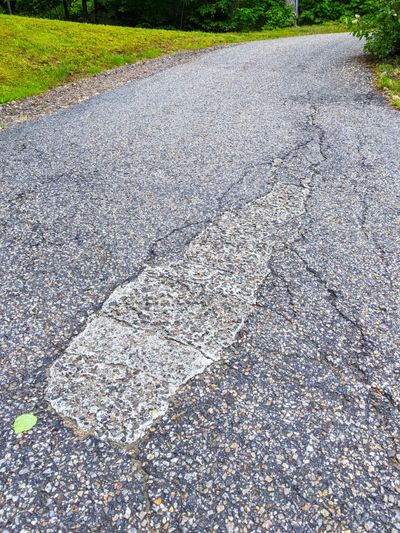 The homeowner repaired a sinking hole in this blacktop drive using epoxy and stones. It’s time to cut it out and install real hot mix asphalt.  (Tribune Content Agency)