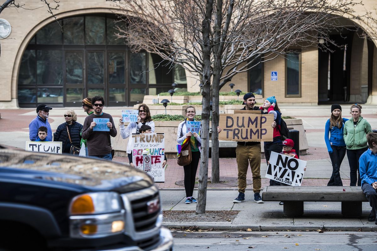 An anti-Trump gathering displays  protest signs to passing motorists, Nov. 12, 2016, outside the United States Federal Courthouse in downtown Spokane, Wash. (Dan Pelle / The Spokesman-Review)